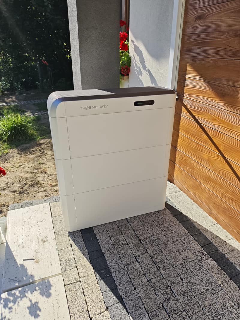Magazyn energii SigenStor 21 kWh ustawiony na zewnątrz, przy elewacji budynku