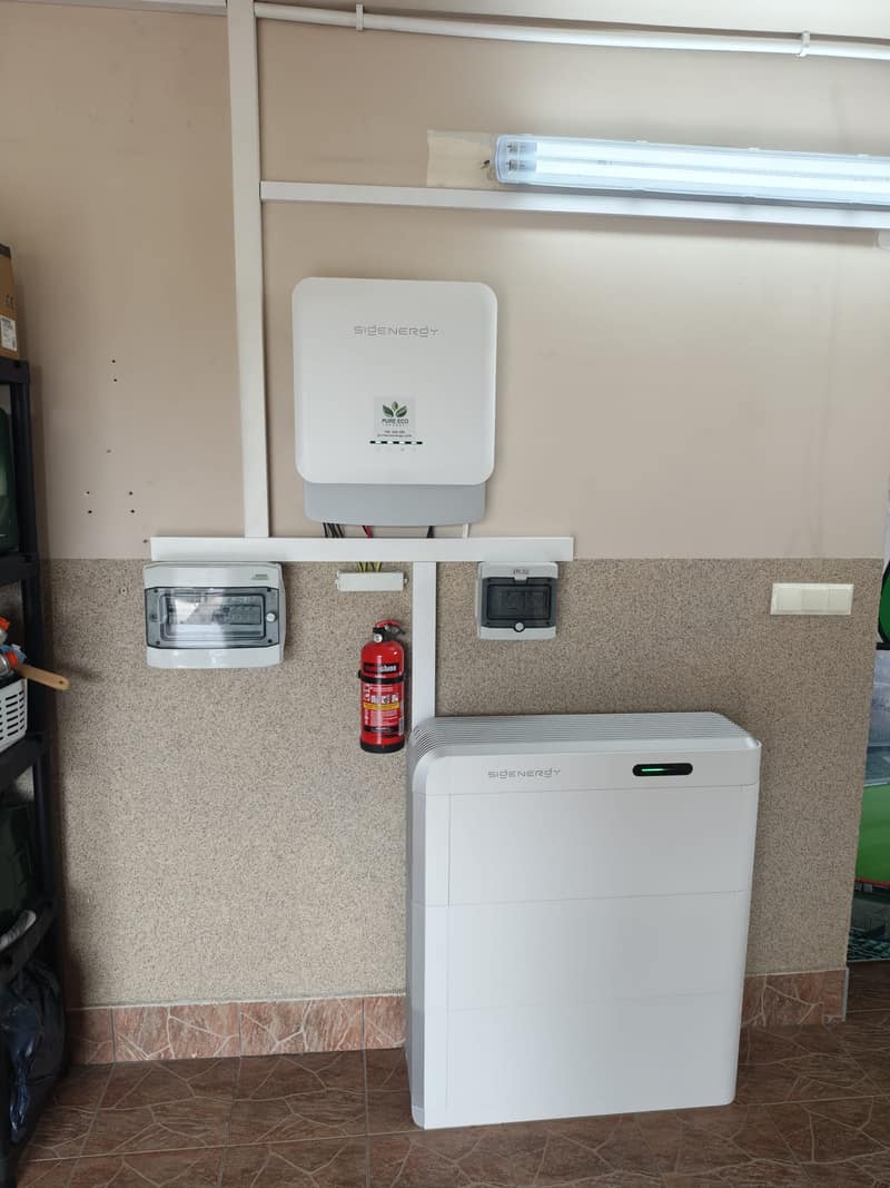 Falownik hybrydowy Sigenergy z magazynem energii SigenStor 24 kWh w garażu — obok gaśnica